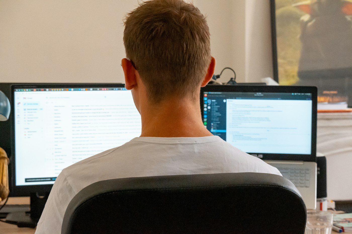 Person von hinten an einem Arbeitsplatz mit zwei Monitoren